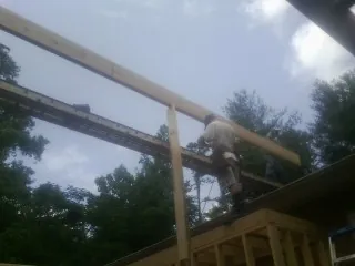 Carpenter setting a ridge beam over a new addition frame — Ice Dam Removal by Roofing Brothers in Antigo