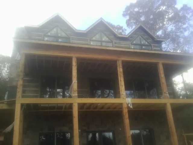 Dormers and porch framing on a large log home under construction — Roof Coating work by our crew in Antigo