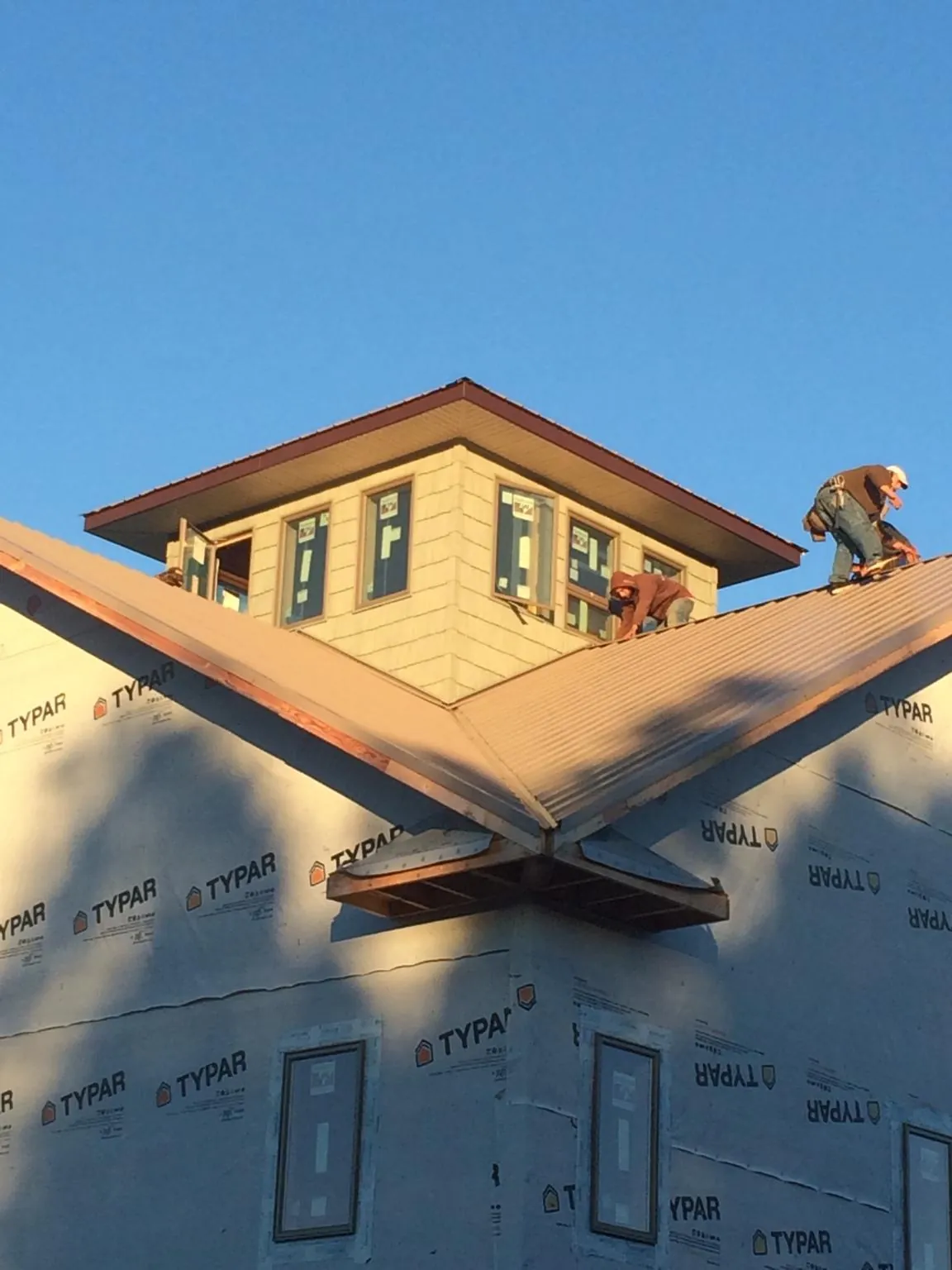 Roofers working around a rooftop cupola on a new metal roof at sunset — Roof Waterproofing in Antigo by Roofing Brothers